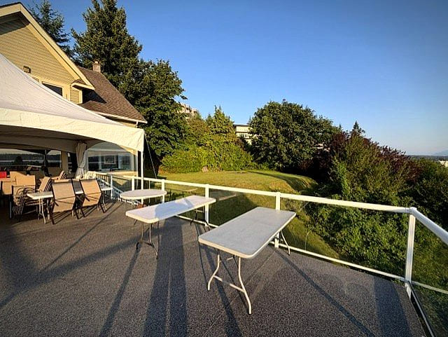 Tables set out along the deck for a celebration, greenery and view beyond
