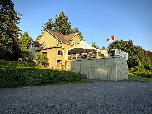 The Club's clubhouse and deck above downtown Campbell River in warm evening light, Canadian flag flying